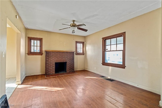 unfurnished living room featuring a fireplace, light hardwood / wood-style flooring, and ceiling fan