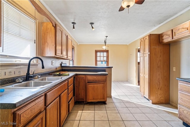 kitchen featuring sink, light tile patterned floors, hanging light fixtures, a textured ceiling, and kitchen peninsula