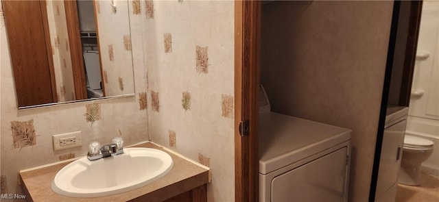 bathroom featuring vanity, washer / clothes dryer, and toilet