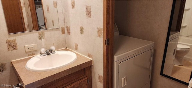 bathroom featuring washer / clothes dryer, vanity, and toilet