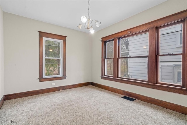 empty room with carpet flooring and a chandelier