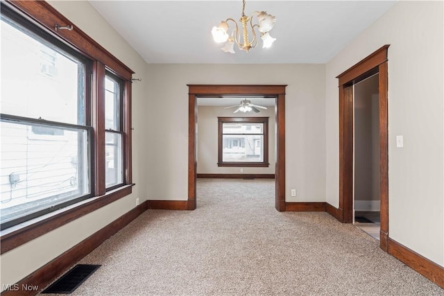 hall with a wealth of natural light, light carpet, and a chandelier