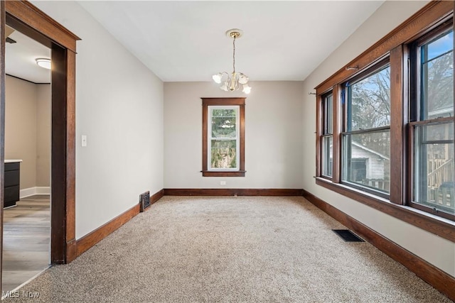 carpeted empty room featuring a chandelier