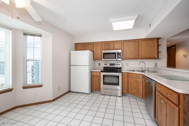 kitchen with appliances with stainless steel finishes, sink, light tile patterned floors, and plenty of natural light