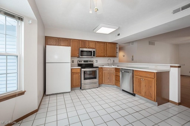 kitchen with appliances with stainless steel finishes, plenty of natural light, sink, and kitchen peninsula