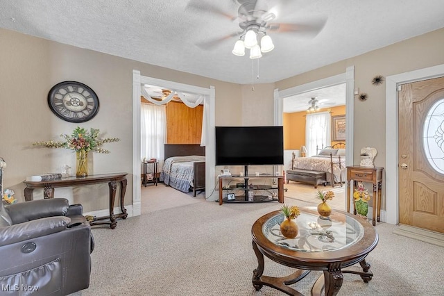 carpeted living room with ceiling fan and a textured ceiling