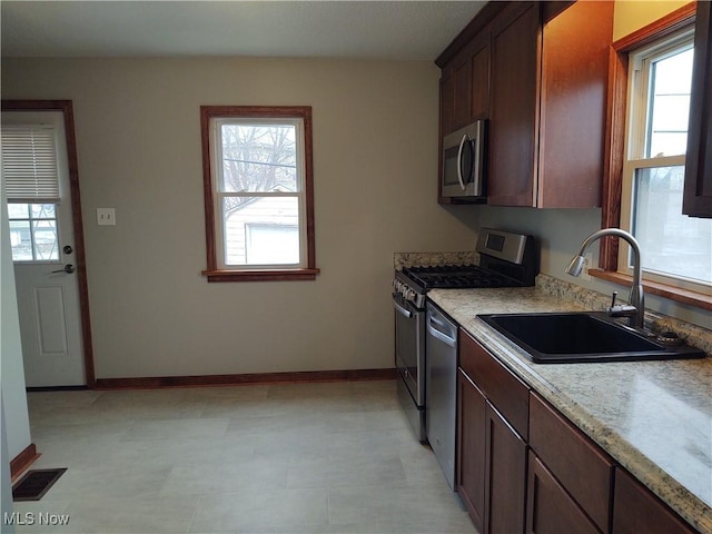 kitchen with a healthy amount of sunlight, appliances with stainless steel finishes, sink, and dark brown cabinetry