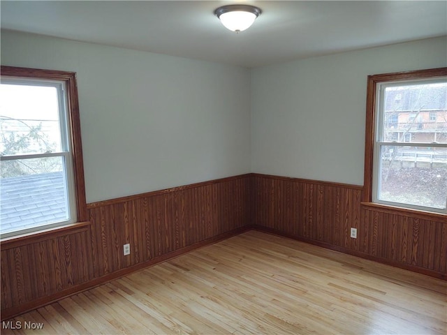 empty room with wooden walls and light wood-type flooring