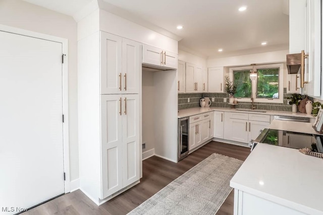 kitchen with dark hardwood / wood-style floors, white cabinetry, sink, beverage cooler, and backsplash