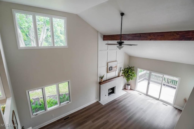 unfurnished living room with a large fireplace, wood-type flooring, lofted ceiling with beams, and plenty of natural light