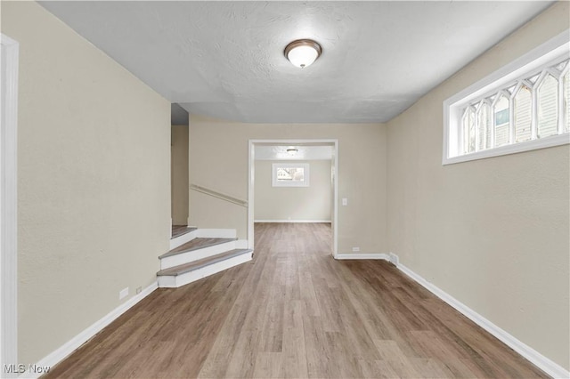 corridor featuring a textured ceiling and light hardwood / wood-style floors