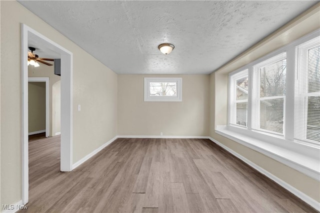 spare room with a textured ceiling and light wood-type flooring