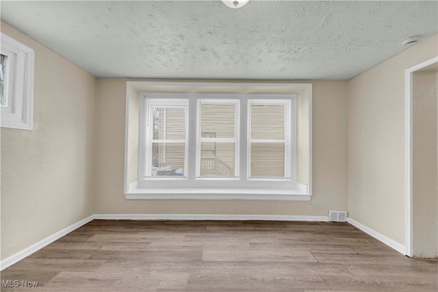 spare room featuring a textured ceiling and light wood-type flooring