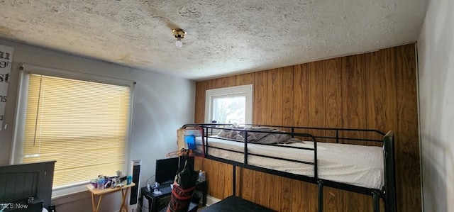 bedroom with a textured ceiling and wood walls