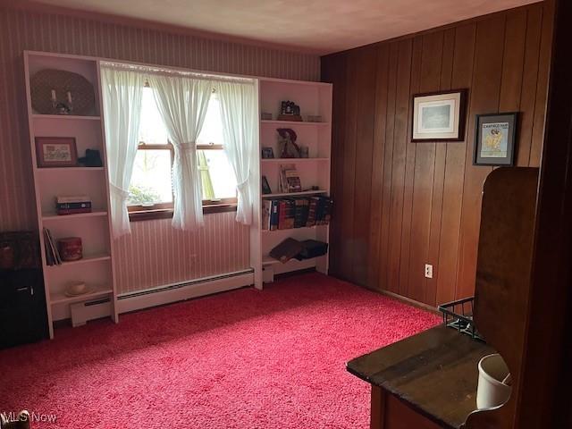 living area with carpet floors, wooden walls, and baseboard heating