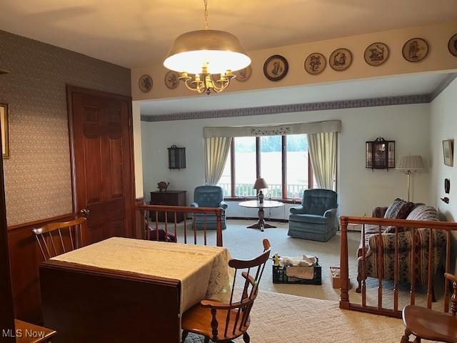 carpeted dining area with a chandelier