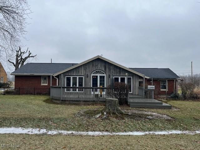 single story home featuring a wooden deck and a front yard