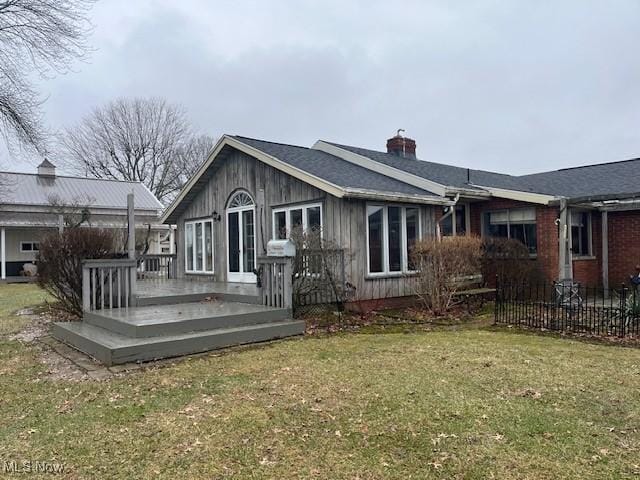 back of property featuring a deck and a lawn