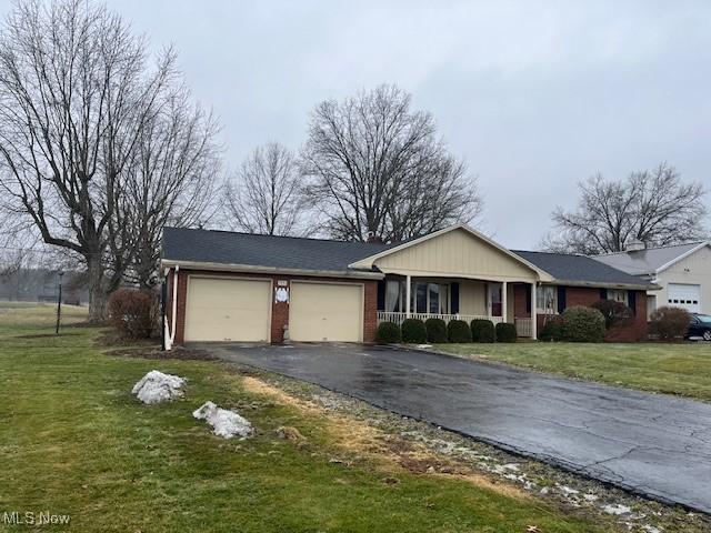 single story home with a garage, covered porch, and a front yard