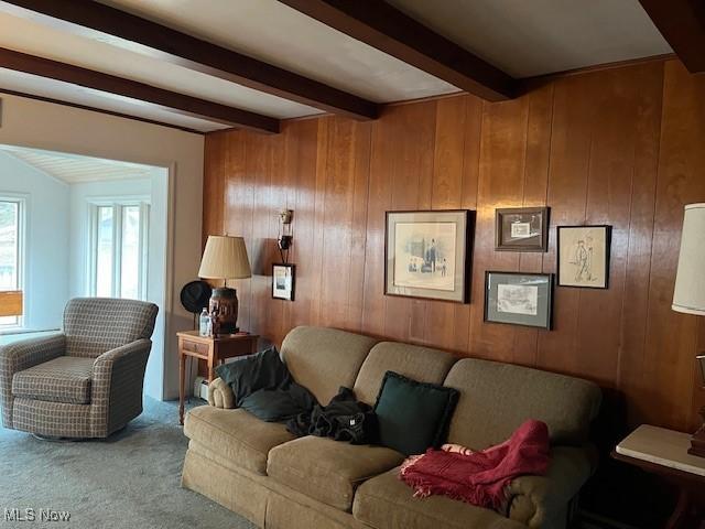 carpeted living room with wooden walls and beamed ceiling