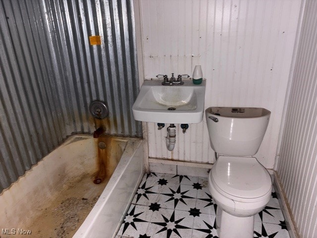 bathroom featuring toilet, sink, and a bath