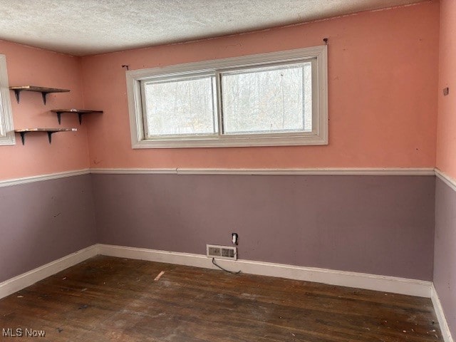 interior space with dark hardwood / wood-style flooring, hookup for a washing machine, and a textured ceiling