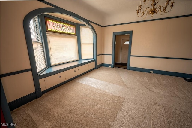 carpeted spare room with a healthy amount of sunlight and a notable chandelier