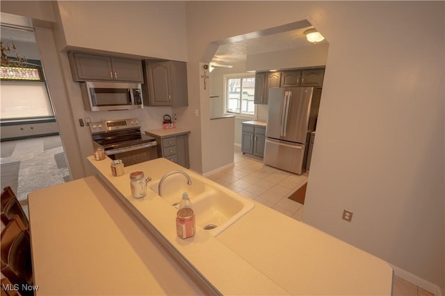 kitchen featuring light tile patterned floors, gray cabinets, sink, and appliances with stainless steel finishes