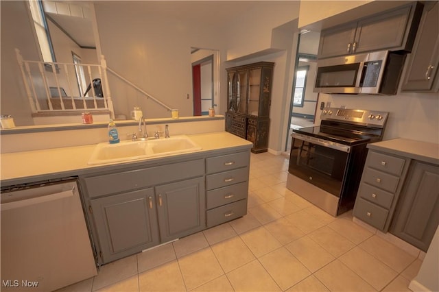 kitchen featuring stainless steel appliances, light tile patterned flooring, sink, and gray cabinets