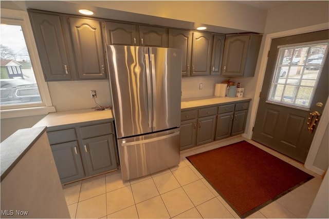 kitchen featuring gray cabinets, light tile patterned flooring, and stainless steel refrigerator