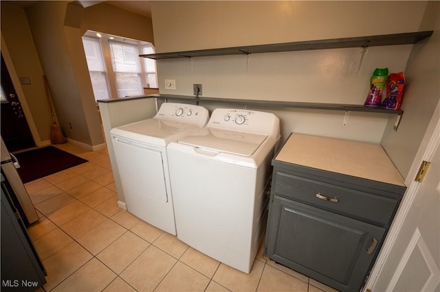 clothes washing area featuring cabinets, separate washer and dryer, and light tile patterned floors