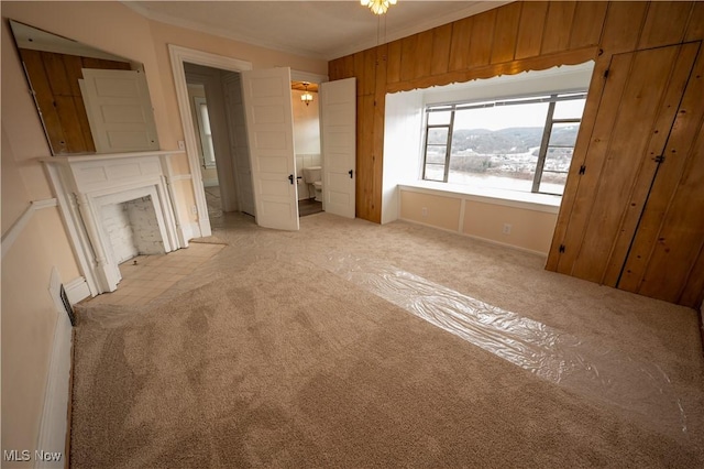 unfurnished bedroom featuring crown molding, light colored carpet, and wooden walls