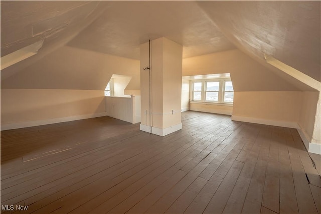 additional living space with dark wood-type flooring and vaulted ceiling