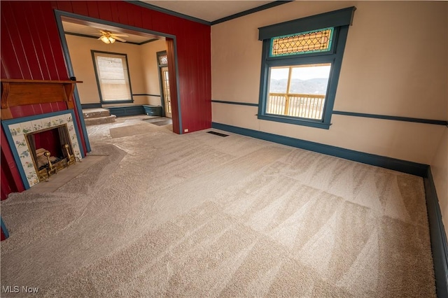 unfurnished living room with light carpet, a fireplace, ornamental molding, and ceiling fan