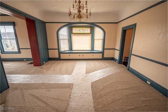 carpeted empty room featuring a healthy amount of sunlight and an inviting chandelier