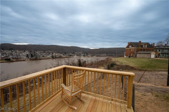 deck with a water view and a lawn