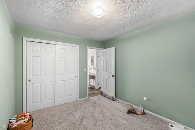 unfurnished bedroom with carpet, a textured ceiling, and a closet