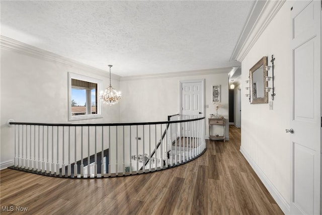 corridor featuring wood-type flooring, crown molding, a chandelier, and a textured ceiling