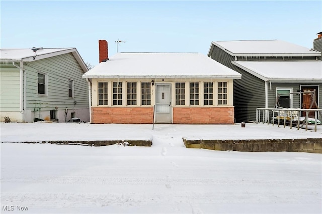 snow covered rear of property with a chimney