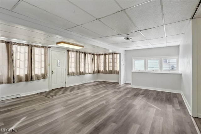 interior space with wood finished floors, a paneled ceiling, and baseboards