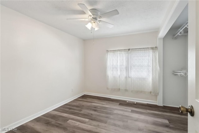 spare room with a ceiling fan, a textured ceiling, baseboards, and dark wood-style flooring