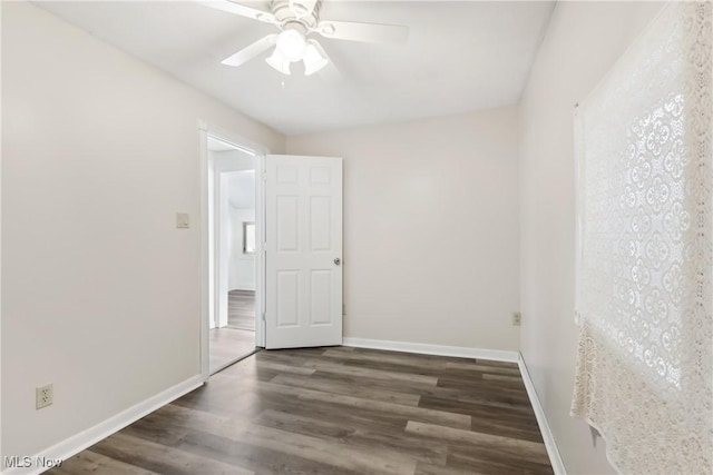 empty room with dark wood-type flooring, baseboards, and a ceiling fan