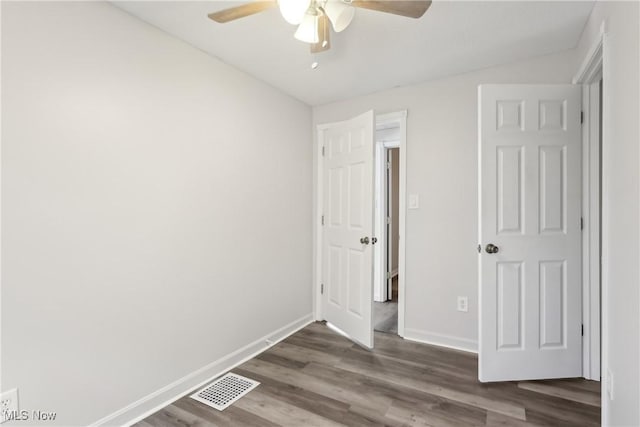 unfurnished bedroom featuring dark wood-style floors, baseboards, visible vents, and a ceiling fan