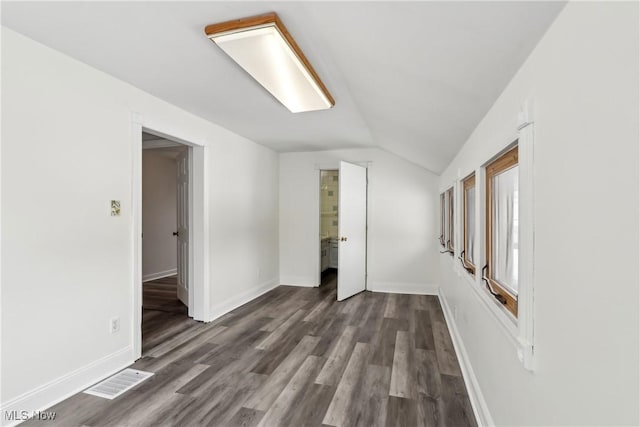 interior space with lofted ceiling, dark wood-style flooring, visible vents, and baseboards