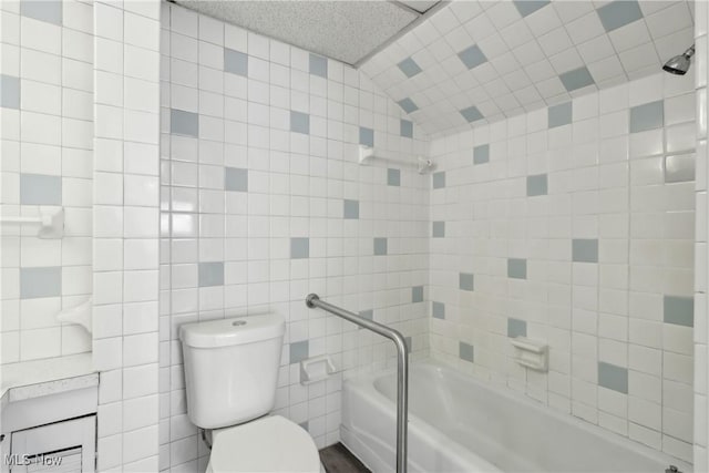 bathroom featuring tile walls, toilet, and a tub