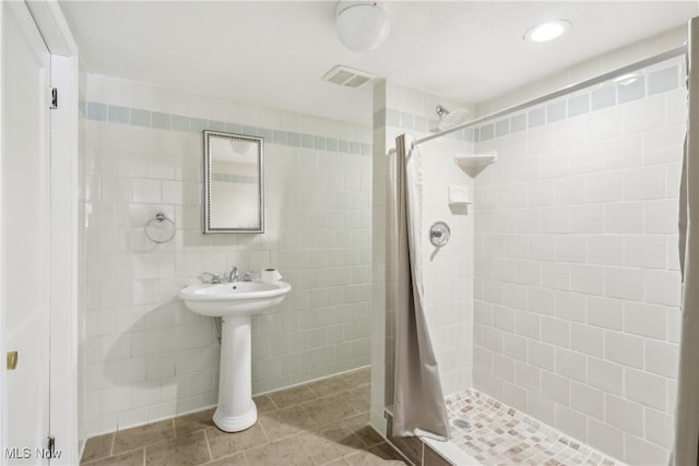 full bath featuring a stall shower, tile patterned flooring, visible vents, and tile walls