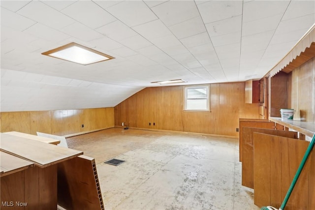 bonus room featuring vaulted ceiling, concrete floors, visible vents, and wooden walls