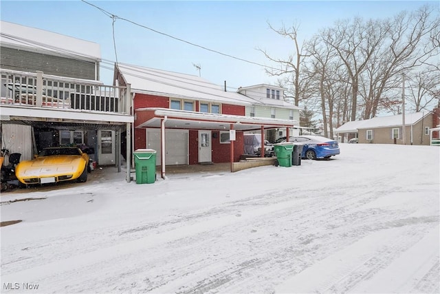 snow covered house featuring a garage and brick siding