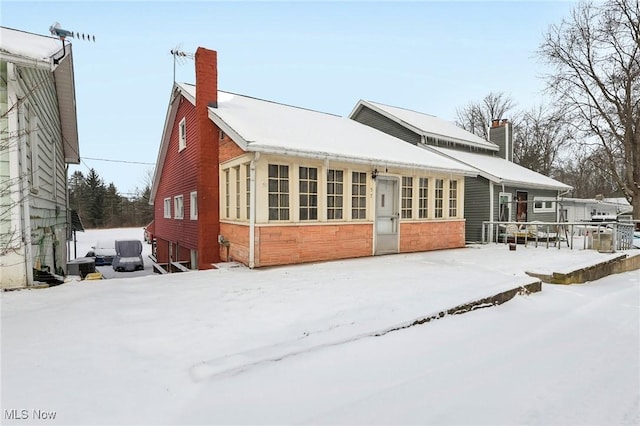 snow covered house featuring a chimney