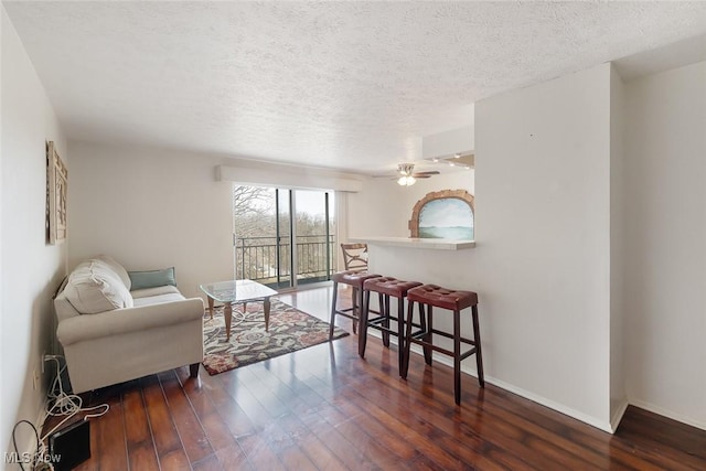 sitting room with dark hardwood / wood-style floors, a textured ceiling, and ceiling fan